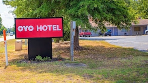 Señal de OYO Hotel con una vista despejada del entorno, que incluye un estacionamiento y un edificio al fondo.