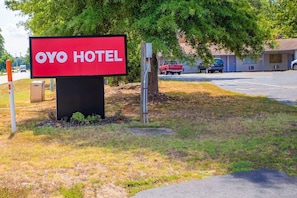 Señal de OYO Hotel con una vista despejada del entorno, que incluye un estacionamiento y un edificio al fondo.
