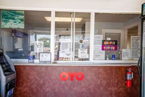 Ein Motel-Empfangsbereich mit Check-in-Schalter, einem Feuerlöscher und einem großen OYO-Logo an der Wand.