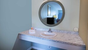 A bathroom with a marble sink, a round mirror, and a light fixture above the mirror. - Kernersville NC|King Bed (Kernersville NC)