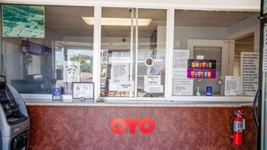 A motel reception desk with a check-in counter, a fire extinguisher, and a large OYO logo on the wall. - Kernersville NC|King Bed (Kernersville NC)