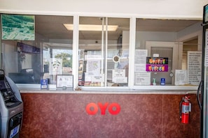 En motelreception med en indtjekningsdisk, en brandslukker og et stort OYO-logo på væggen.