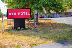 Schild für Hotel OYO mit freiem Blick auf die Umgebung, darunter ein Parkplatz und ein Gebäude im Hintergrund.