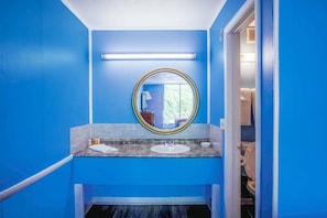 A bathroom with blue walls, a round mirror, two sinks, and a visible toilet. - Kernersville NC|Queen Bed (Kernersville NC)