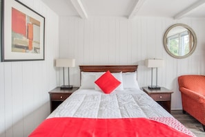 A neatly arranged bedroom with a bed, two bedside tables, a chair, a mirror, and a framed picture on the wall. - Kernersville NC|Queen Bed (Kernersville NC)