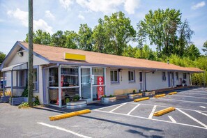 Ein Motel mit überdachter Eingangspartie, Parkplatz und Schild mit 30% Rabatt.