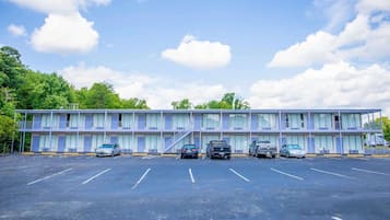 Um motel com estacionamento, vários quartos e uma escada que leva ao andar superior.