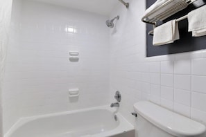Ein Badezimmer mit Badewanne, Toilette und Handtuchhalter mit Handtüchern.