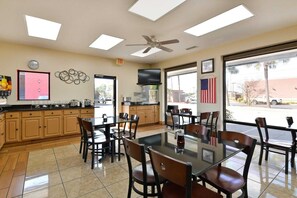 Un restaurant doté d’un espace cuisine, de tables, de chaises, d’un ventilateur de plafond et d’un drapeau américain.