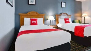 Dos camas dobles con ropa de cama roja y blanca, cabeceros de madera, lámparas de noche y cuadros en las paredes.
