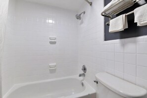 Ein Badezimmer mit Badewanne, Toilette und Handtuchhalter mit Handtüchern.