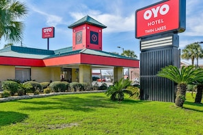 Un hôtel à la façade rouge et verte, doté d’une tour horloge et d’une enseigne indiquant qu’il s’agit de l’h ôtel OYO Twin Lakes.