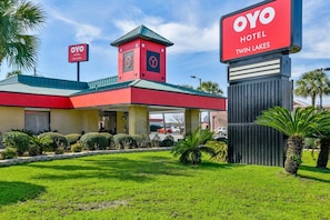 A hotel with a red and yellow facade, a clock tower, and a signboard.