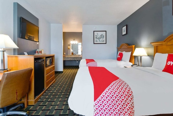 A hotel room with a bed, desk, chair, and a view of the bathroom.