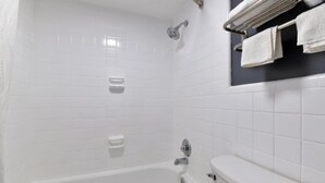 A bathroom with a bathtub, toilet, and a towel rack with towels.