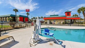 A hotel with a pool, a lifeguard stand, and a red building with a clock tower.