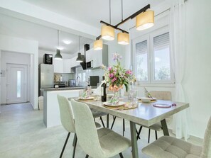 A modern kitchen with a dining area, featuring a central island, pendant lighting, and a vase with flowers. - Luxury Villa Gaby With Heated Pool (Sali)