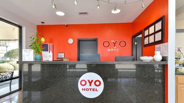 A reception desk with a red wall, a clock, and a sign that reads 'OYO HOTEL'.