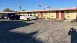 Un motel avec une rangée de chambres, un parking et quelques palmiers en arrière-plan.