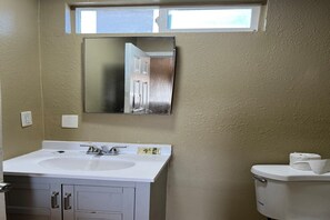 Ein Badezimmer mit einem weißen Waschbecken, einem Spiegel und einer Toilette.