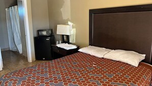 Une chambre d’hôtel avec un lit, une table de chevet, une lampe, un téléviseur et une porte de salle de bain.