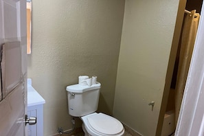 Un baño pequeño con inodoro, un mueble blanco y cortina de ducha.