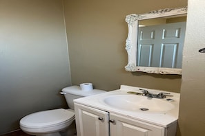 Un baño con inodoro, lavabo y espejo.