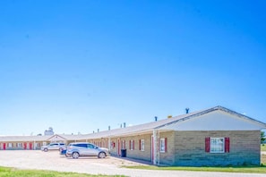 A motel with multiple rooms, a parking area, and a small building with red shutters.