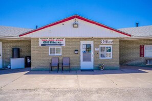 Un edificio de ladrillo con una puerta blanca y un letrero que dice 'Green Acres Motel Office'.