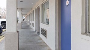 A corridor with a row of rooms, each with a window and a door. - Premium 2 Queen Bed|Nsmk (DeRidder LA)