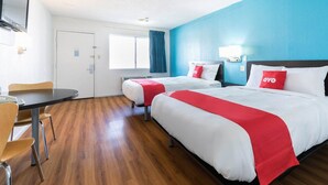 A hotel room with two beds, a dining table, and a TV. - Premium 2 Queen Bed|Nsmk (DeRidder LA)