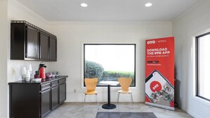 A modern kitchen with dark cabinets, a black countertop, two chairs, a small round table, and a large window.