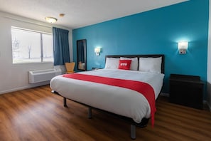 Una habitación de hotel con cama, ventana, calefactor y mesita de noche.