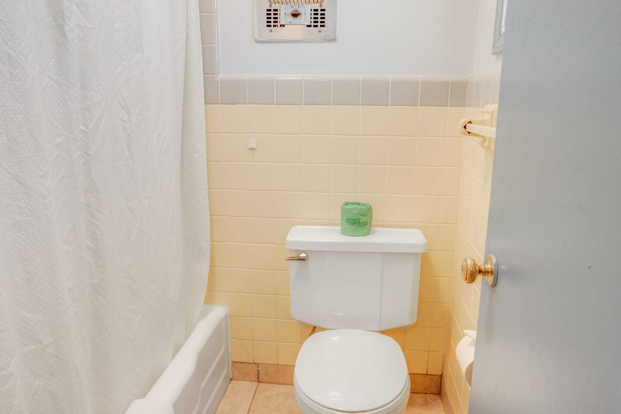 Un baño pequeño con inodoro, cortina de ducha y dispensador de papel higiénico.