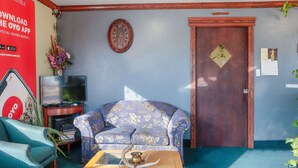A living room with a sofa, a coffee table, a TV, and a door. - Liberal KS|2 Full Bed (Liberal KS)