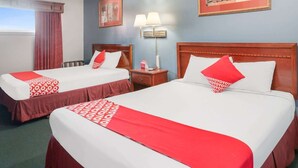 Two double beds with red and white bedding, a nightstand with a lamp, and a window with curtains. - Liberal KS|2 Full Bed (Liberal KS)