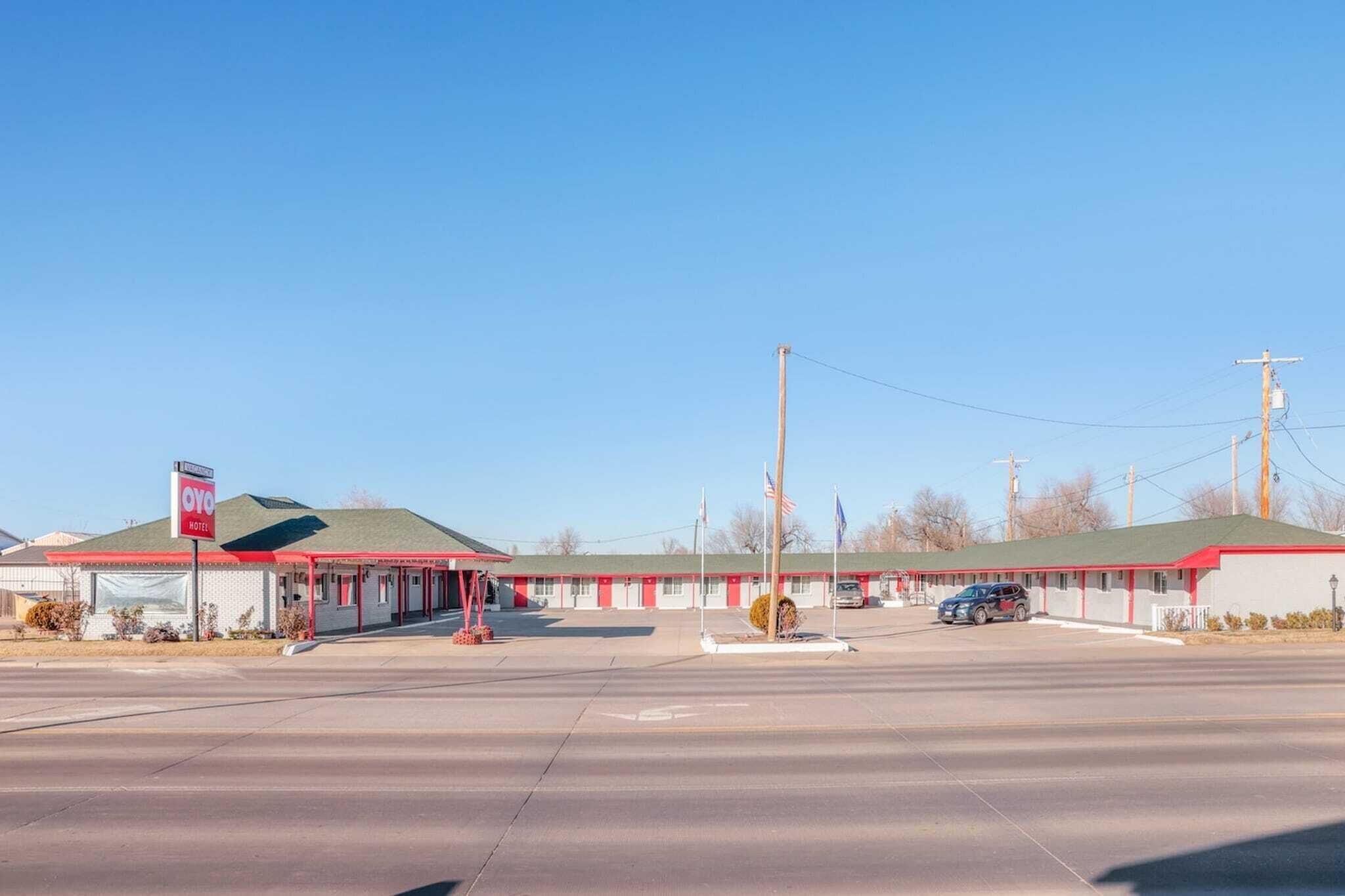 A motel with a red and white exterior, a covered parking area, and a clear blue sky.