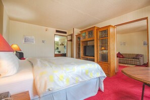 A hotel room with a bed, a TV, a wooden cabinet, and a red carpet.