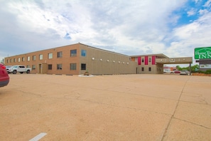 A hotel with a parking lot, a building with a flat roof, and a sign for Home To Inn.