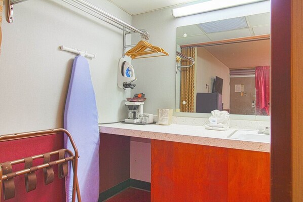 Une salle de bain équipée d’un lavabo, d’un miroir, d’un porte-serviettes et d’un étendoir à vêtements.