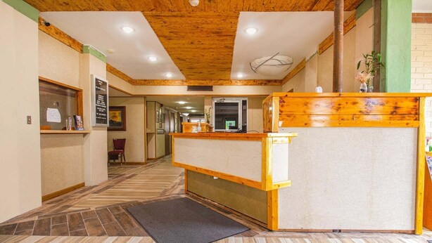 A hotel lobby with a wooden reception desk, a reception area, and a tiled floor.