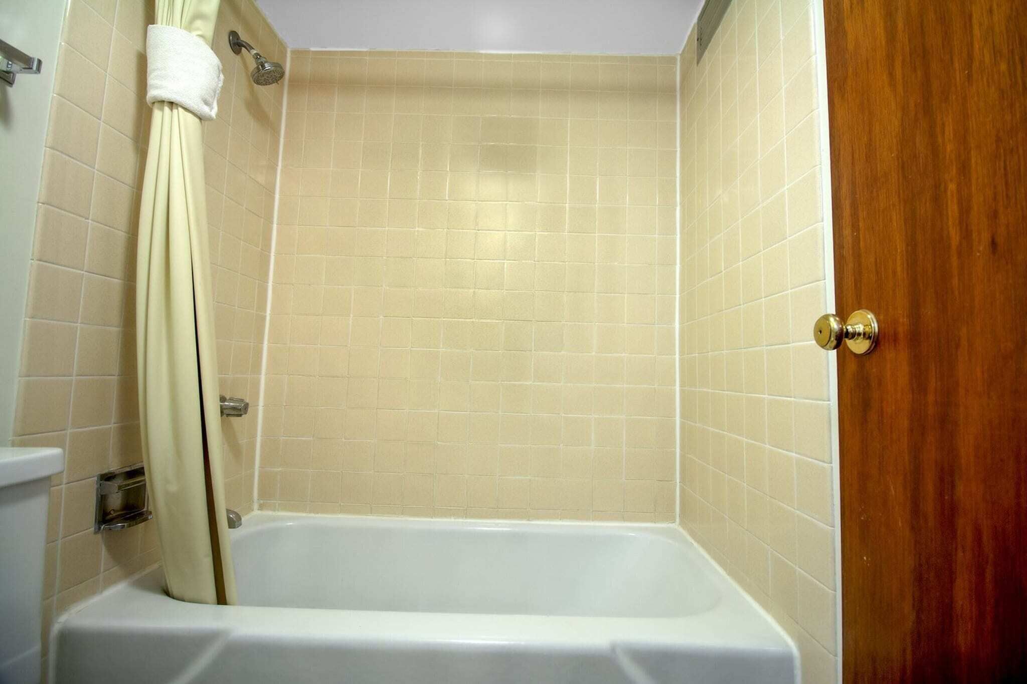 Un baño con bañera, cortina de ducha y puerta de madera.