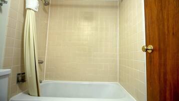 Un baño con bañera, cortina de ducha y puerta de madera.