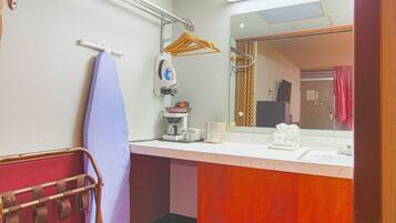 A bathroom with a sink, mirror, towel rack, and a hanging clothes rack.