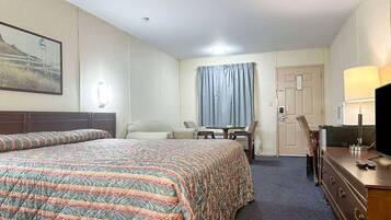 A hotel room with a bed, a desk, a chair, a dresser, a television, and a window with curtains.