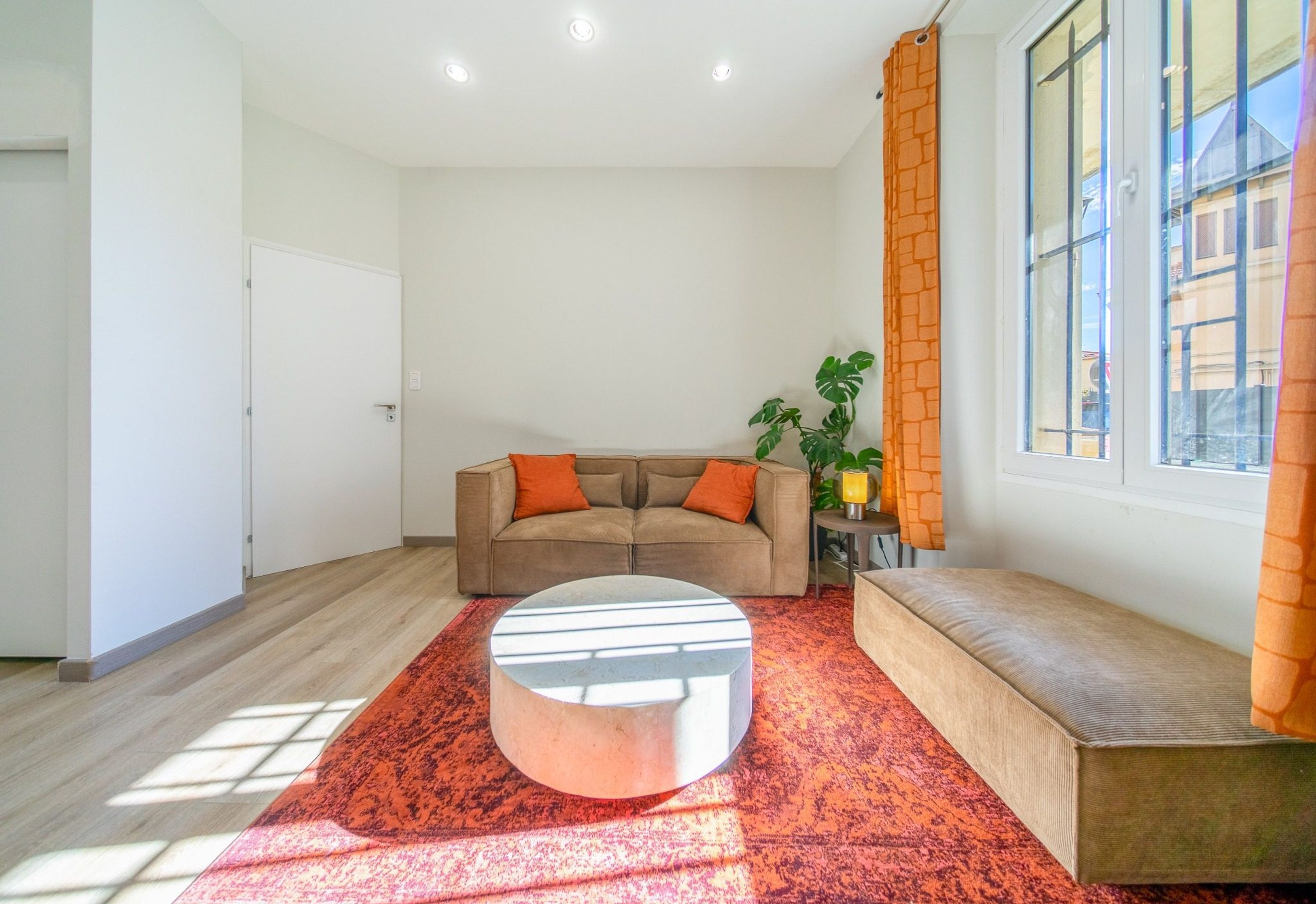 A living room with a sofa, ottoman, and a plant.