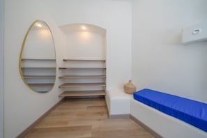 Ein schmaler Korridor mit Holzboden, einer blauen gepolsterten Bank und einem an der Wand befestigten Regal mit einem Korb.