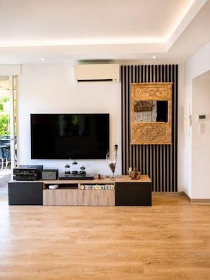 A modern living room with a large flat-screen TV, a wooden entertainment unit, and a decorative wall panel. - 225 Le Club C in Cannes (Cannes)