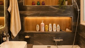 A modern bathroom with a bathtub, a shower, and shelves with toiletries. - 225 Le Club C in Cannes (Cannes)