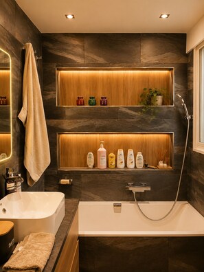 A modern bathroom with a bathtub, a shower, and shelves with toiletries. - 225 Le Club C in Cannes (Cannes)